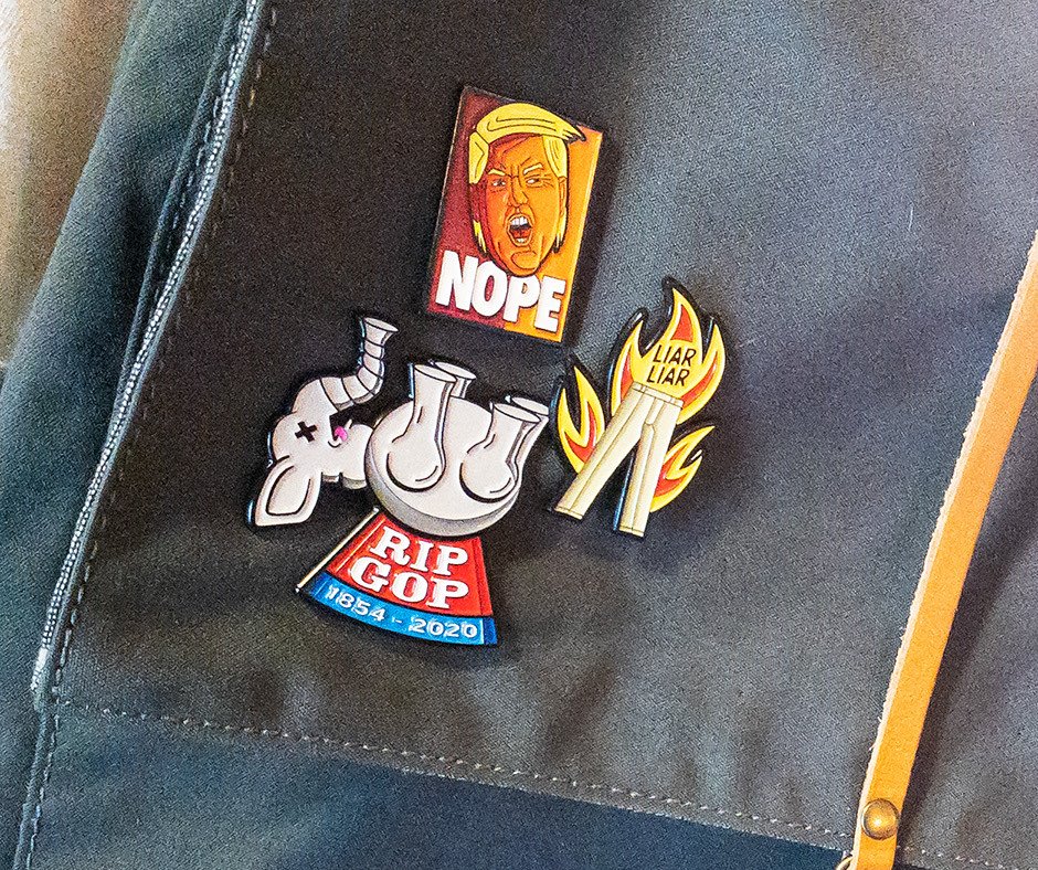 NOPE, RIP GOP and Liar Liar pins worn together on a canvas backpack strap