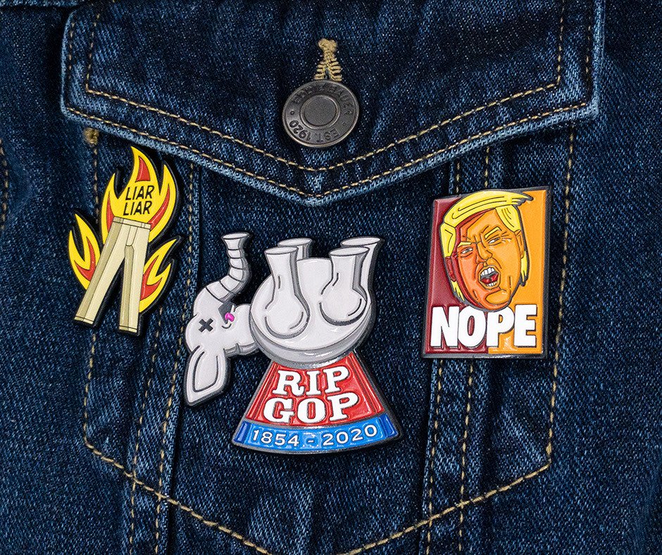 Three Pintacular enamel pins pinned to a denim jacket pocket