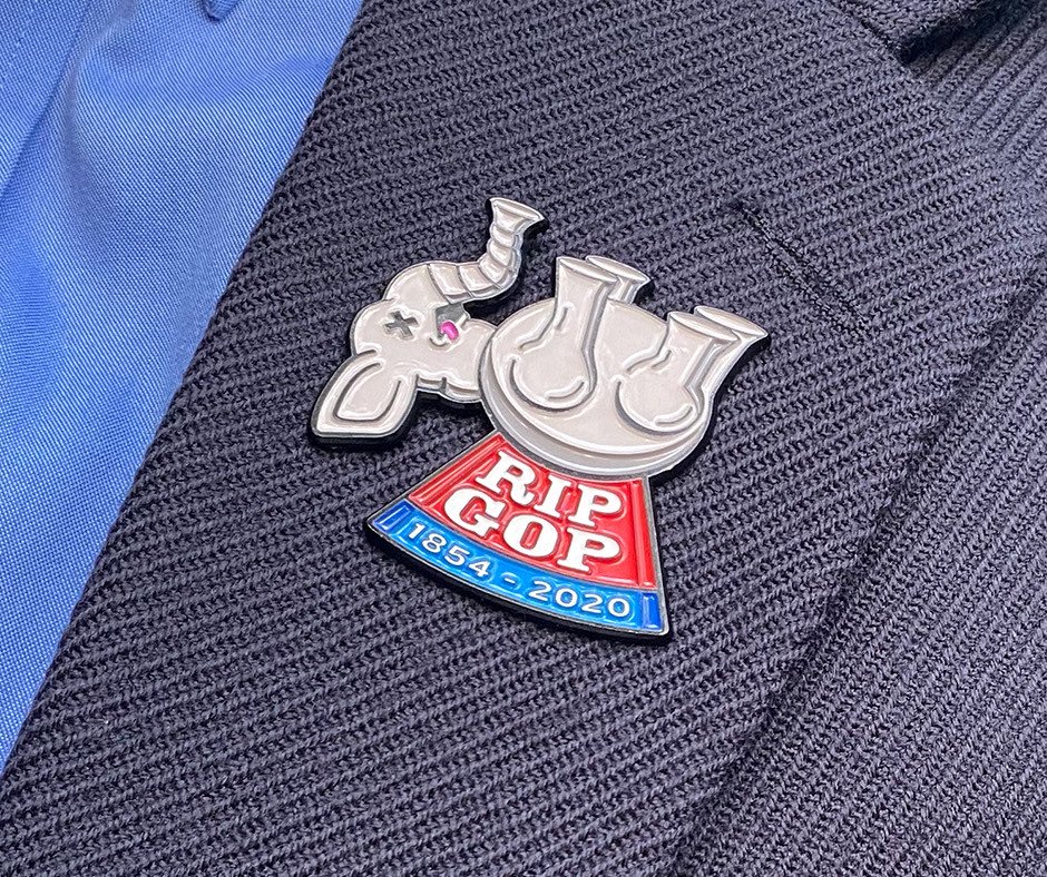 RIP GOP enamel pin worn on the lapel of a dark suit blazer
